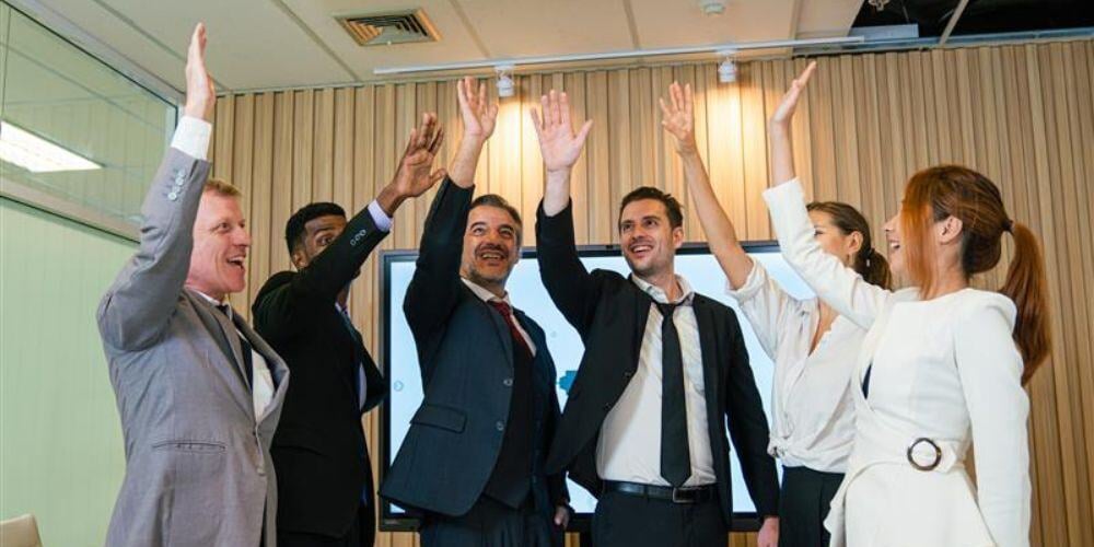 A group of professionals celebrating successful IPO transition planning with MSP guidance in a modern boardroom setting