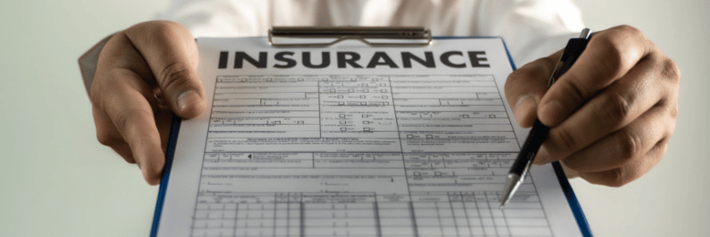 A person in a white shirt is holding an insurance form attached to a blue clipboard, ready to fill it out with a black pen.