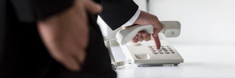 Businessman dialing a landline phone, comparing landlines vs VoIP options for government communication needs