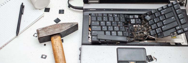 Destroyed laptop with a hammer highlighting the physical destruction method in hardware disposal