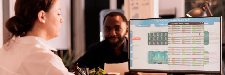 Employees discussing the pros and cons of employee monitoring for BYOD policies on a data analysis screen