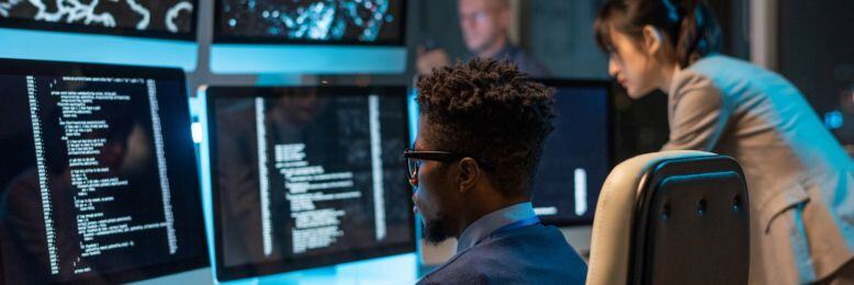 IT professionals monitoring security data on multiple screens, focused on vulnerability management strategies