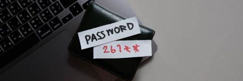 Laptop with a note stating a weak password example, highlighting the need for strong password policies