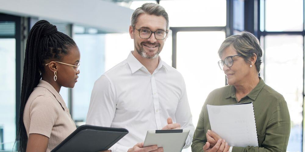 Professionals collaborating with documents and a tablet, focusing on essential questions to ask before selecting an MSP in Chicago