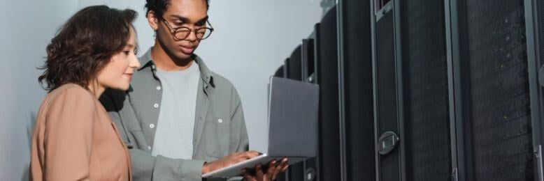 Team members in a server room discussing IT strategies, highlighting a conversation on in-house vs outsourced IT solutions for the public sector