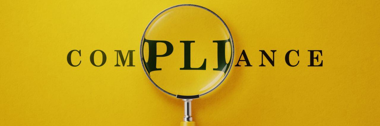 the word compliance with a magnifying glass over the word